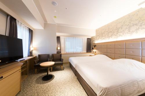 a hotel room with a bed and a flat screen tv at Kobe Luminous Hotel Sannomiya in Kobe