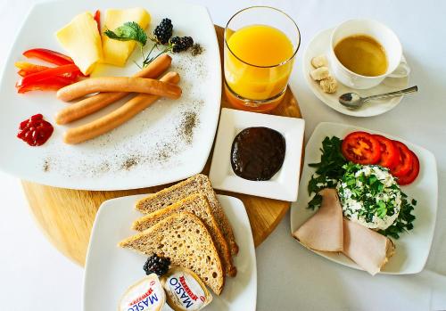 a table with plates of food and a glass of orange juice at IRS ROYAL APARTMENTS Apartamenty IRS Aviator in Gdańsk