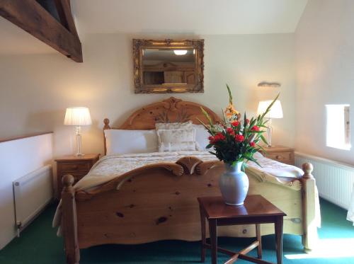 Bretton Cottage في إيام: غرفة نوم مع سرير خشبي مع إناء من الزهور على طاولة