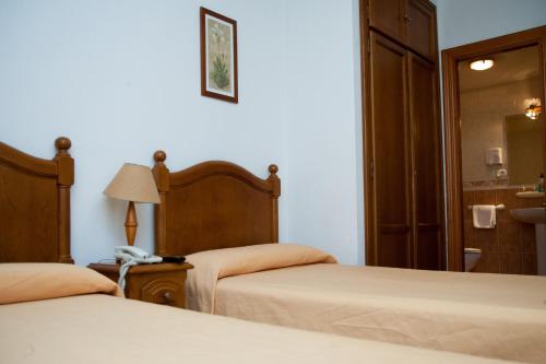 a hotel room with two beds and a mirror at Hostal El Rincón in Avila