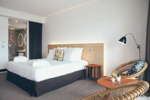 a hotel room with a bed and a table and a chair at Hôtel & Spa Villa Seren in Hossegor