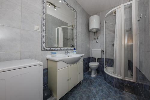 ein Badezimmer mit einem Waschbecken, einem WC und einem Spiegel in der Unterkunft Apartment Botic in Kaštela