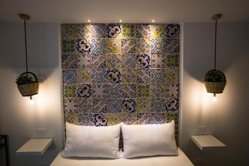 a bedroom with a headboard with a colorful wall at Acquarò Suite in San Vito lo Capo