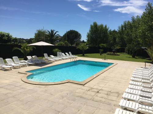 a swimming pool with chairs and an umbrella at la ferme des 4 chenes in Urt