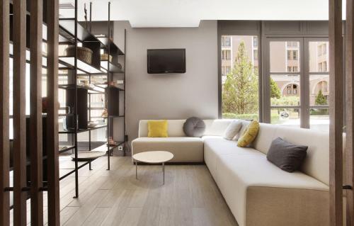 een woonkamer met een witte bank en een tv bij Odalys City Aix en Provence L'Atrium in Aix-en-Provence