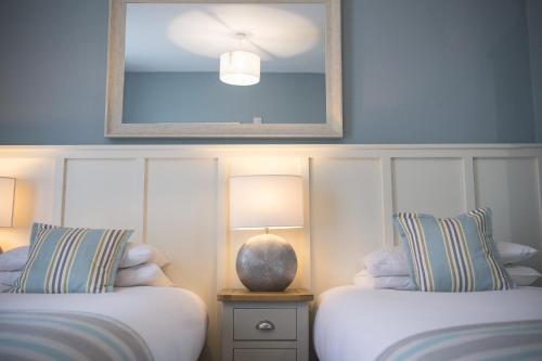 a bedroom with two beds and a mirror on the wall at George Hotel, BW Signature Collection in Norwich