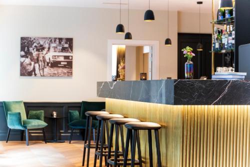 a row of stools in a bar with green chairs at Hotel Acacia in Bruges
