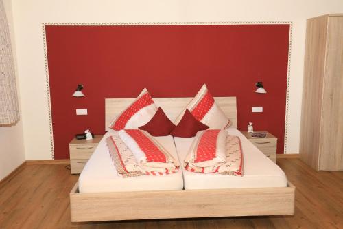 a bed with red and white pillows on it at Gasthof Beim Endeler in Missen-Wilhams