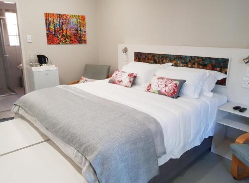 sypialnia z dużym łóżkiem z białą pościelą i poduszkami w obiekcie A Country Garden Guest House w mieście Potchefstroom