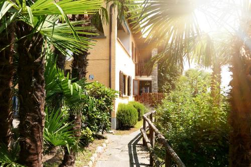 une maison avec une clôture et des palmiers devant elle dans l'établissement Reka-Ferienanlage Brissago, à Brissago