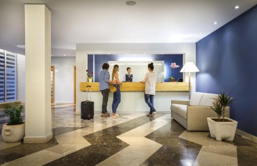 a group of people standing at a bar in a lobby at Aminess Younique Lume Hotel in Brna