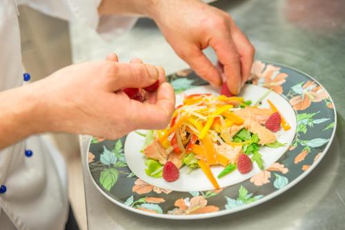 a person holding a plate of food on a table at Hotel Alla Posta - Famiglia Pra dal 1866 a Caprile in Alleghe