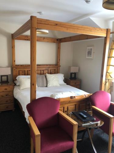 1 dormitorio con 1 cama con marco de madera y 2 sillas en Laragh House B&B en Kilkenny