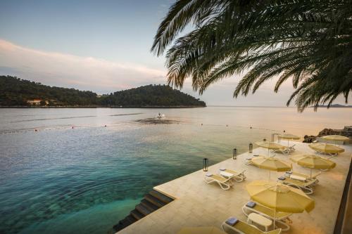 a pool with yellow umbrellas and chairs and the water at Aminess Younique Lume Hotel in Brna