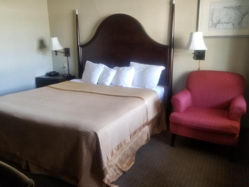 um quarto de hotel com uma cama e uma cadeira vermelha em Inn at Mulberry Grove em Port Wentworth