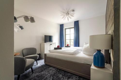 a bedroom with a bed and a chair and a window at Pension Kleiner König in Struppen-Siedlung