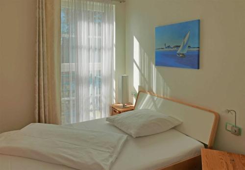 a bedroom with a white bed with a window at Baabe Gruene Duene Fewo Strandroma in Baabe