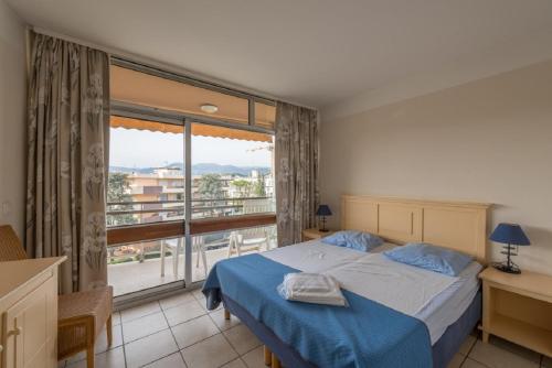 une chambre avec un lit et une grande fenêtre dans l'établissement Residence Heliotel Marine - maeva Home, à Saint-Laurent-du-Var