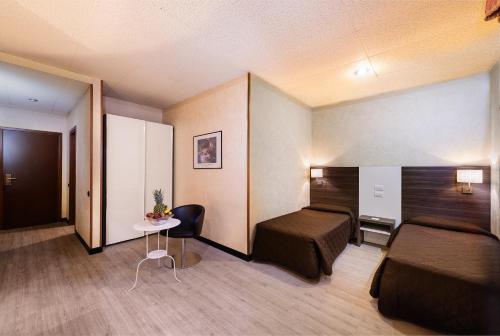 a hotel room with two beds and a table at JR Hotels Bologna Amadeus in Bologna