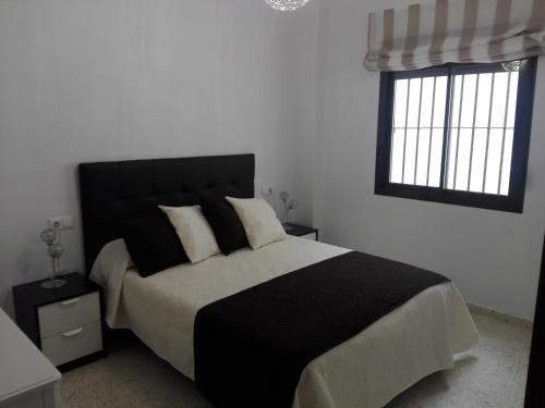 サンルーカル・デ・バラメダにあるApartamento ateneoのベッドルーム1室(黒と白のベッド1台、窓2つ付)