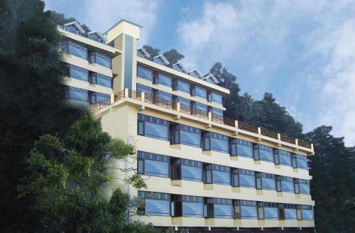 un alto edificio bianco con finestre e alberi blu di Snow Valley Resorts Dalhousie a Dalhousie