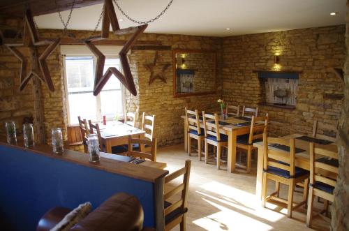 a restaurant with wooden tables and chairs and a brick wall at Chester House Hotel in Bourton on the Water