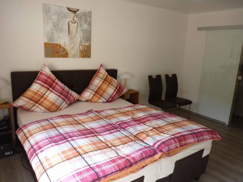 a bedroom with a bed with a plaid blanket and pillows at Ferienwohnung Moselblick in Ediger-Eller