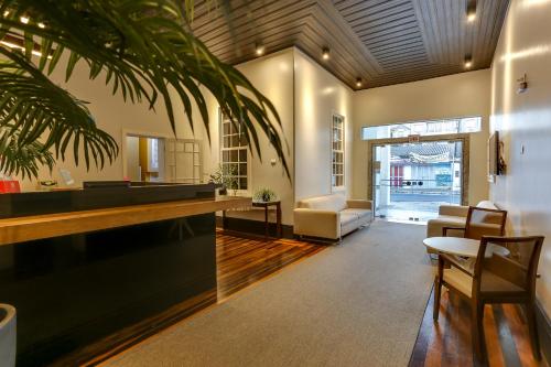 a living room with a couch and a palm tree at Canasvieiras Hotel in Florianópolis