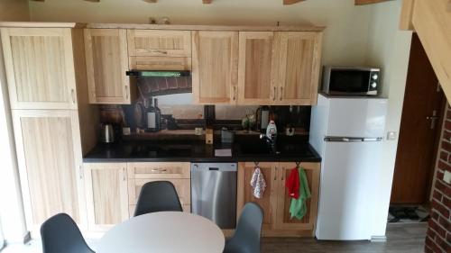 a kitchen with wooden cabinets and a white refrigerator at Domki letniskowe Yaga in Wilkasy