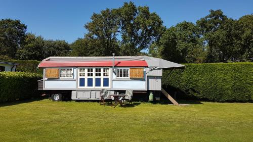 a tiny house with a red roof sitting in a yard at Zigeuner wagen in Oostvoorne