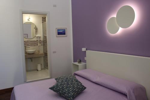 una camera da letto con parete viola, letto e specchio di 319 al Duomo a Napoli