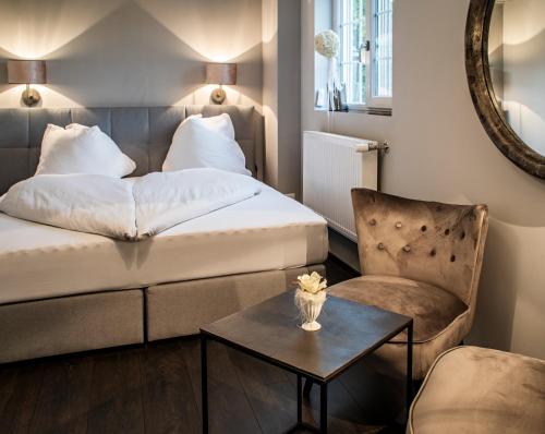 ブルクドルフにあるLandcafe mit Mini Hotelのベッド、椅子、テーブルが備わるホテルルームです。