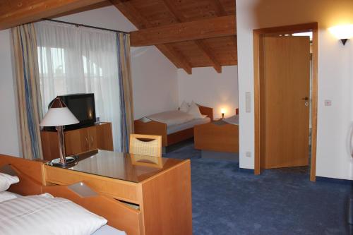 een hotelkamer met een slaapkamer met een bed en een televisie bij Pension Demmel in Bruckmühl