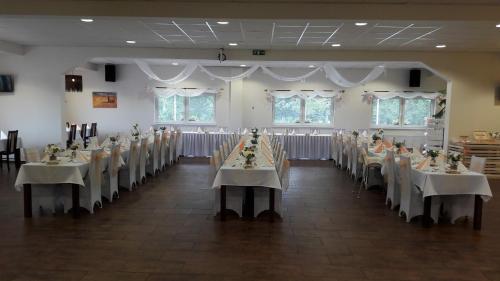 a banquet hall with tables and chairs with white table cloth at Hotel Na Farmě Choťovice in Choťovice