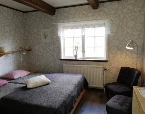a bedroom with two beds and a window and a chair at STF Långasjö Vandrarhem in Långasjö