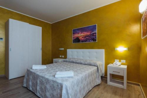 a bedroom with a bed and a yellow wall at Le Vele di Balestrate in Balestrate