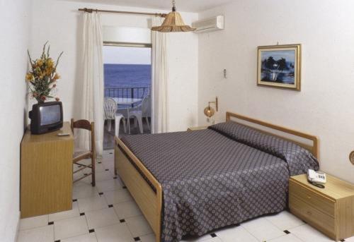 1 dormitorio con cama, TV y balcón en Hotel Solemar, en SantʼAlessio Siculo