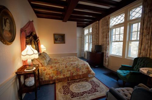 a bedroom with a bed and a chair and window at Cleftstone Manor in Bar Harbor