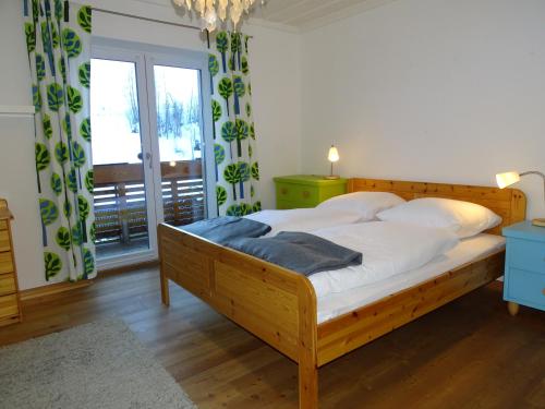 sypialnia z drewnianym łóżkiem z białą pościelą i oknem w obiekcie Alpine Cottage Salzburg w mieście Maria Alm am Steinernen Meer