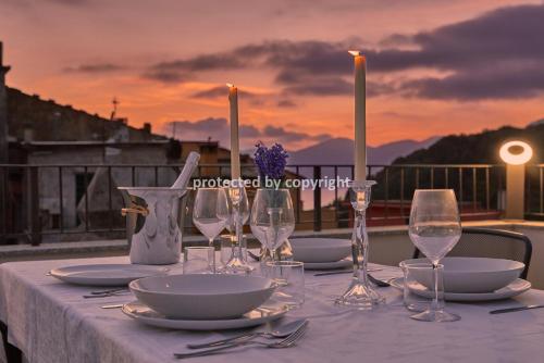 a table with plates and wine glasses on a balcony at Luxury Penthouse Sea View in Corniglia