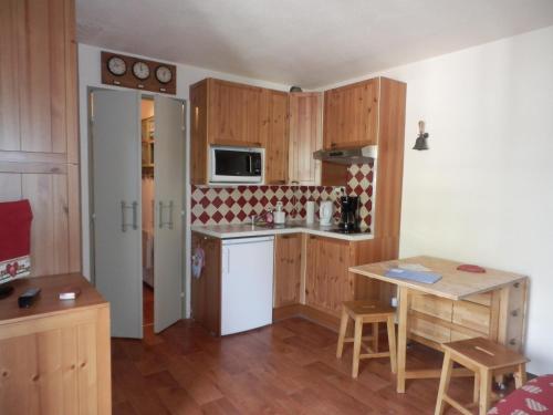 a small kitchen with wooden cabinets and a table at Pluton B63 in Les Deux Alpes