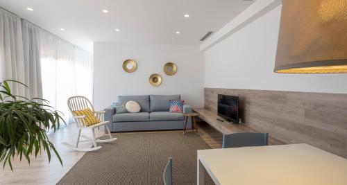 a living room with a couch and a tv at Cliper Apartments by Escampa Hotels in Platja  d'Aro
