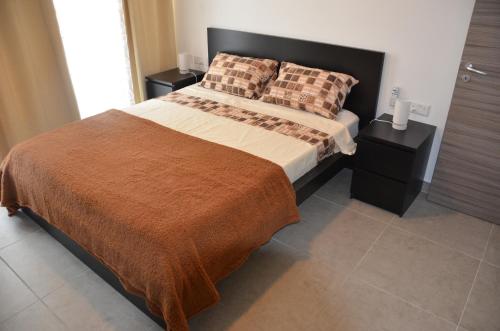 a bedroom with a bed and two night stands at Pilgrim's Rest Apartments in Il-Gżira