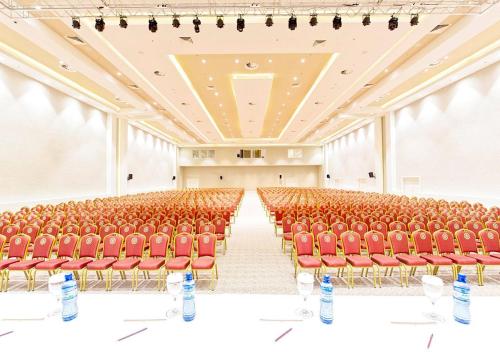 an empty lecture hall with red chairs and tables at Euphoria Batumi Convention & Casino Hotel in Batumi