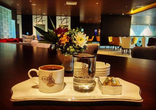 a table with two cups of coffee and a vase of flowers at Euphoria Batumi Convention & Casino Hotel in Batumi