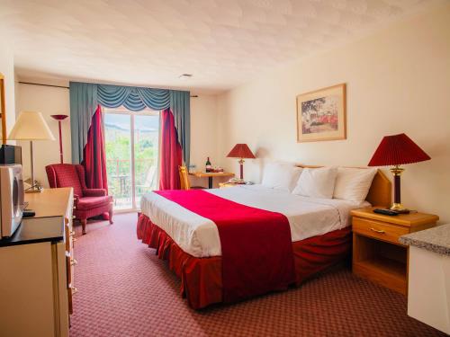 um quarto de hotel com uma cama grande e uma cadeira em Country View Motor Inn em Kamloops