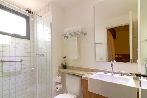 a bathroom with a sink and a toilet and a mirror at Hotel Residences Studio Pinheiros in Sao Paulo