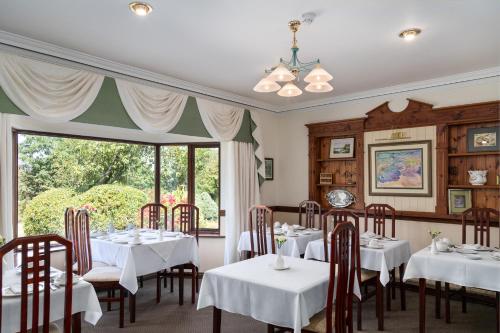 a dining room with white tables and chairs and a window at Kathleens Country House in Killarney