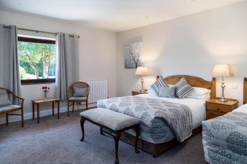 a bedroom with a bed and two chairs and a window at Kathleens Country House in Killarney