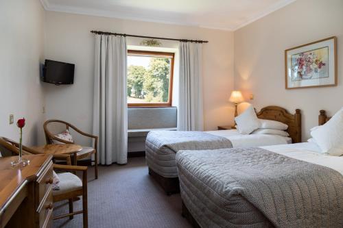 a hotel room with two beds and a window at Kathleens Country House in Killarney